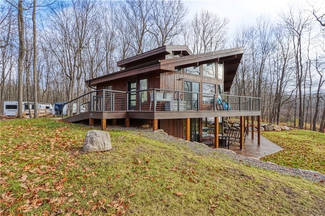 back of house featuring a yard, a patio, and a wooden deck