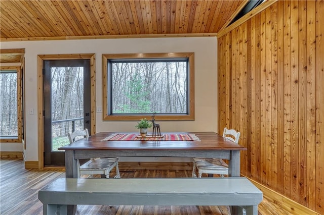 unfurnished dining area with hardwood / wood-style floors, a healthy amount of sunlight, and wood walls