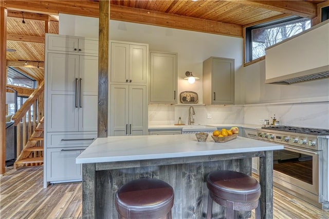 kitchen with a kitchen breakfast bar, stainless steel stove, wooden ceiling, and sink