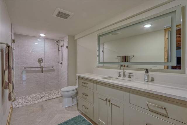 bathroom featuring tiled shower, vanity, and toilet