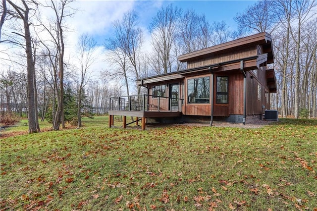 exterior space with a wooden deck, a yard, and cooling unit