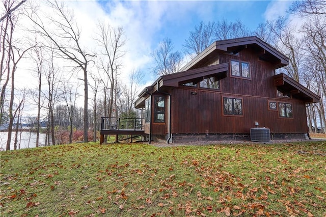 view of side of home with a water view, central AC, and a lawn