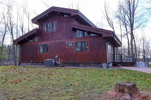 view of side of home featuring a lawn and central AC