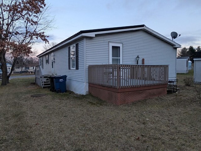 back house at dusk with a lawn and a deck