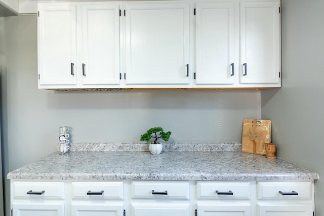 interior space featuring light stone counters and white cabinets