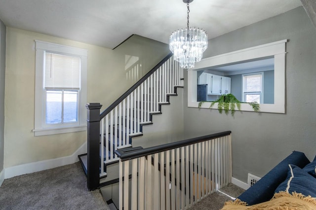 staircase with carpet flooring and an inviting chandelier