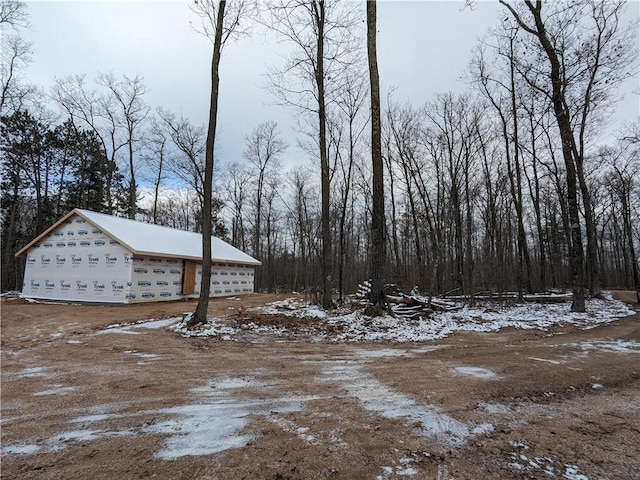 yard covered in snow featuring a garage and an outbuilding