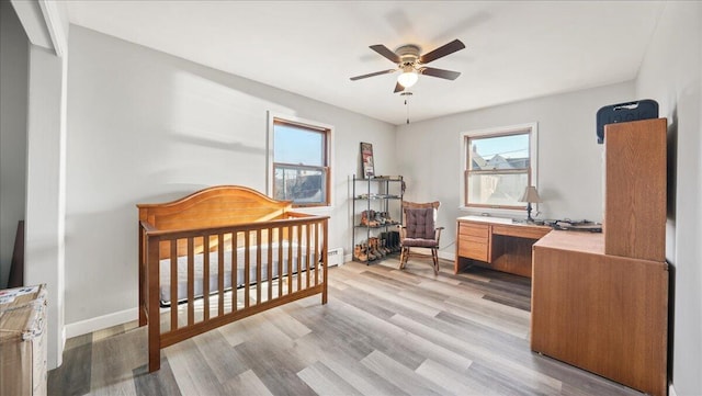 bedroom with ceiling fan, a crib, and light wood-type flooring