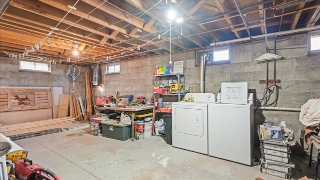 basement with a healthy amount of sunlight, electric panel, and washing machine and clothes dryer