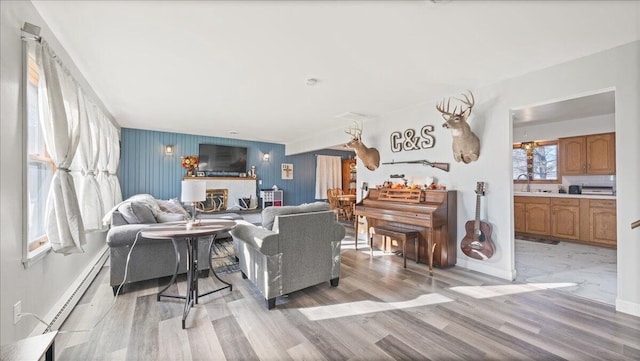 living room with light hardwood / wood-style flooring, a baseboard heating unit, and sink