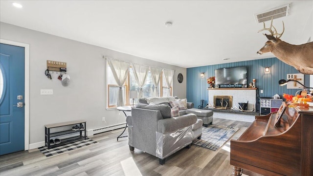 living room with hardwood / wood-style floors, a brick fireplace, and a baseboard heating unit