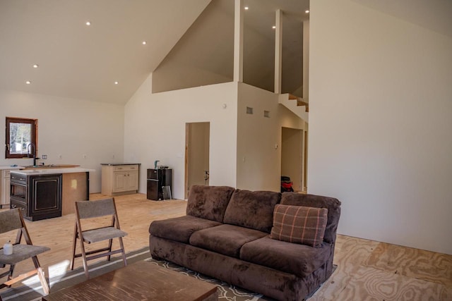 living room featuring sink, high vaulted ceiling, and light wood-type flooring