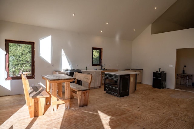 kitchen featuring light wood-type flooring, high vaulted ceiling, and a kitchen island