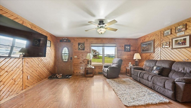 living room with wooden walls, ceiling fan, and wood-type flooring