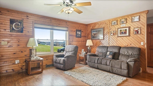 living room featuring wooden walls, hardwood / wood-style floors, and ceiling fan