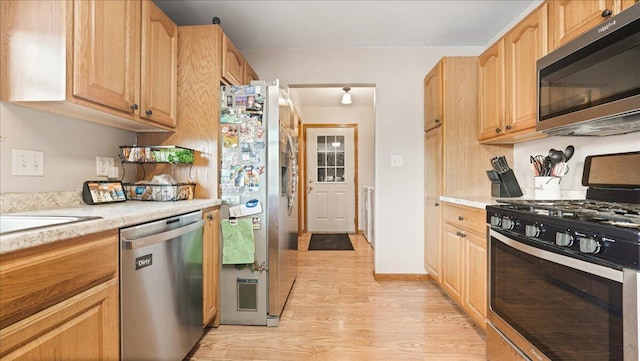 kitchen featuring stainless steel appliances, light brown cabinetry, and light hardwood / wood-style flooring