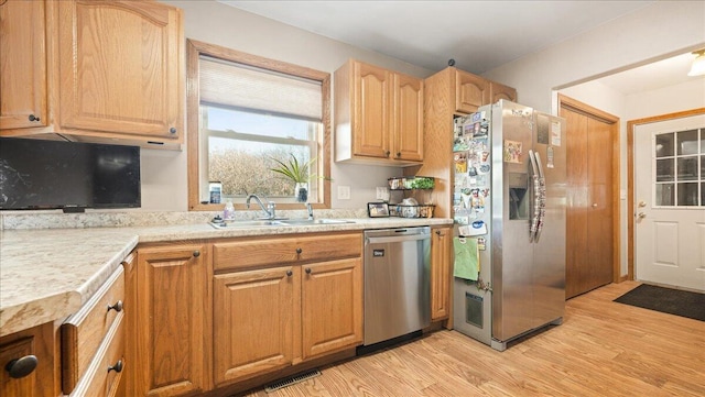 kitchen with sink, stainless steel appliances, and light hardwood / wood-style floors