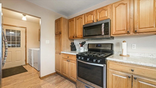 kitchen featuring washer and clothes dryer, light wood-type flooring, and stainless steel appliances