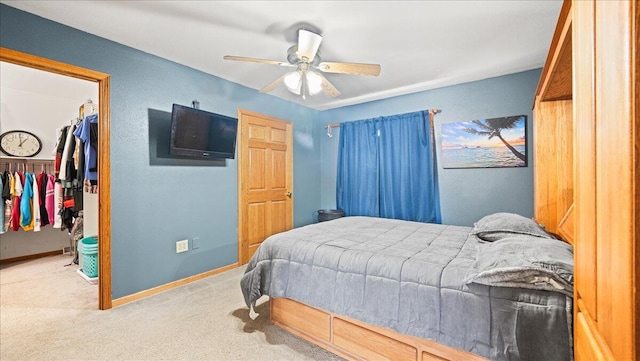 carpeted bedroom with a walk in closet, ceiling fan, and a closet