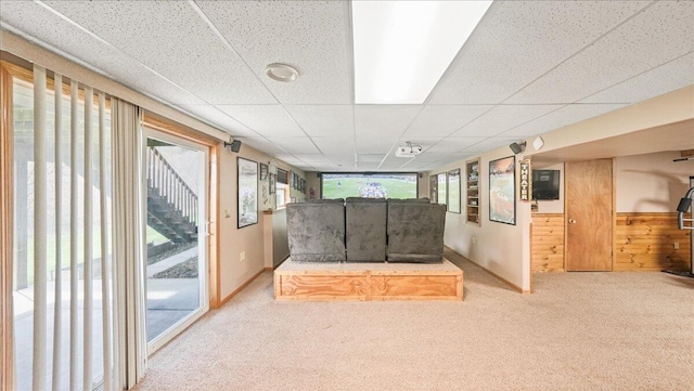 unfurnished room featuring a paneled ceiling, carpet floors, and wooden walls