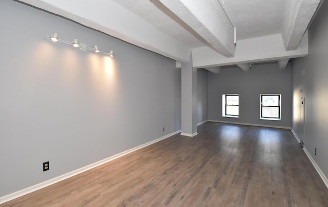 spare room with hardwood / wood-style floors, a textured ceiling, and vaulted ceiling with beams