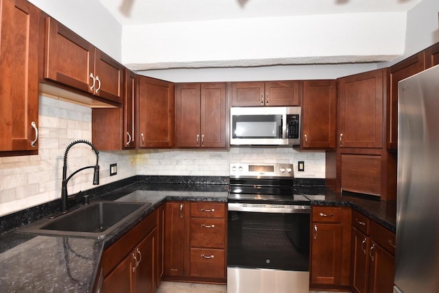 kitchen with dark stone counters, tasteful backsplash, sink, and stainless steel appliances