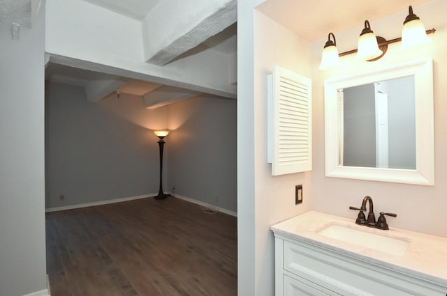 bathroom featuring beamed ceiling, vanity, and hardwood / wood-style flooring