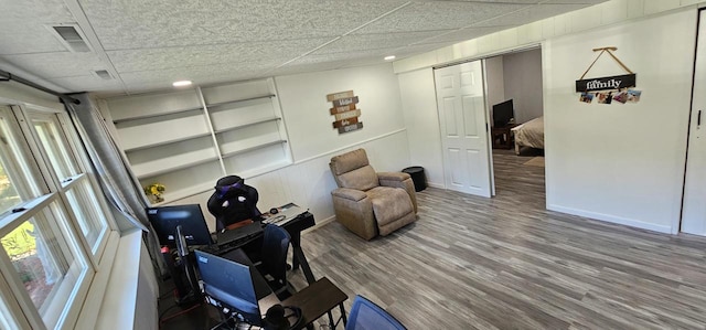 living area with wood-type flooring and a drop ceiling