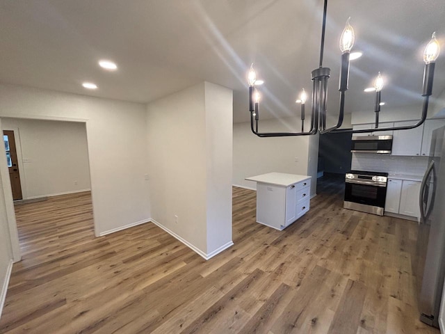 kitchen with hardwood / wood-style floors, a center island, white cabinets, hanging light fixtures, and appliances with stainless steel finishes