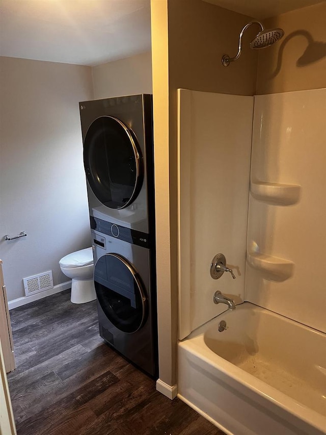 full bathroom with shower / bathing tub combination, stacked washer and dryer, wood-type flooring, toilet, and vanity