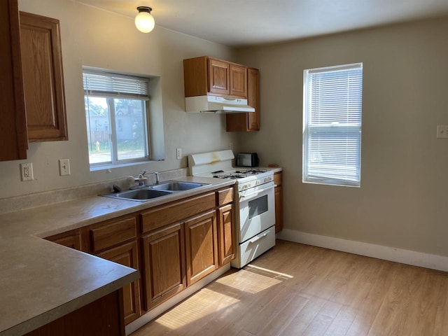 kitchen with light hardwood / wood-style floors, white range with gas stovetop, and sink