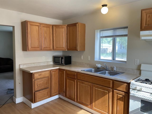 kitchen with ventilation hood, sink, white range with gas stovetop, and light wood-type flooring