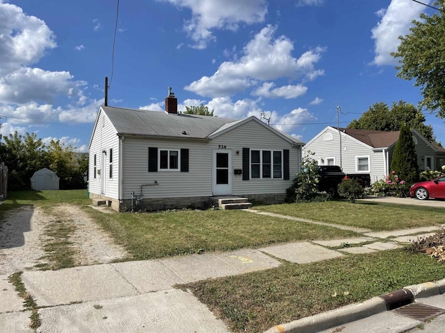 bungalow featuring a front yard and a storage unit