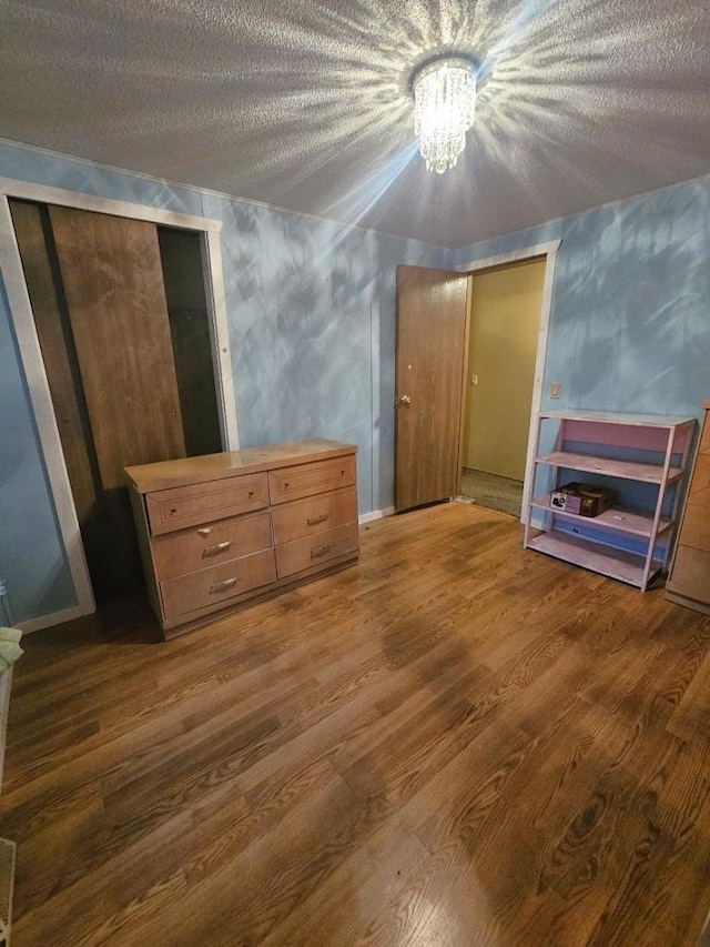 unfurnished bedroom featuring dark hardwood / wood-style flooring, a textured ceiling, and an inviting chandelier