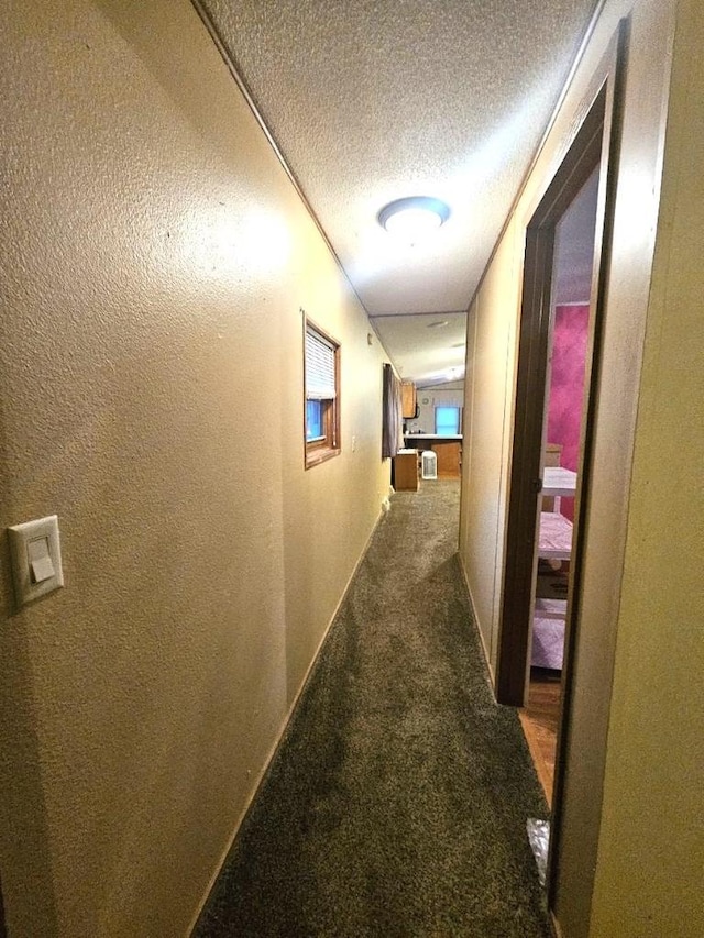 hallway with a textured ceiling and carpet floors