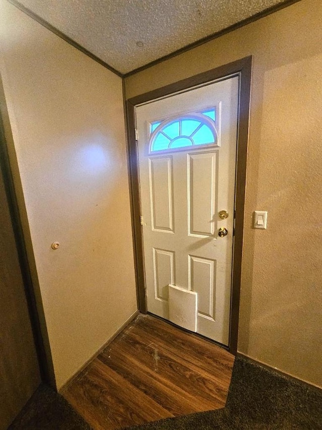 doorway to outside with a textured ceiling and dark wood-type flooring