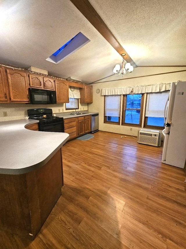 kitchen featuring dark hardwood / wood-style flooring, a textured ceiling, a wall unit AC, black appliances, and a notable chandelier