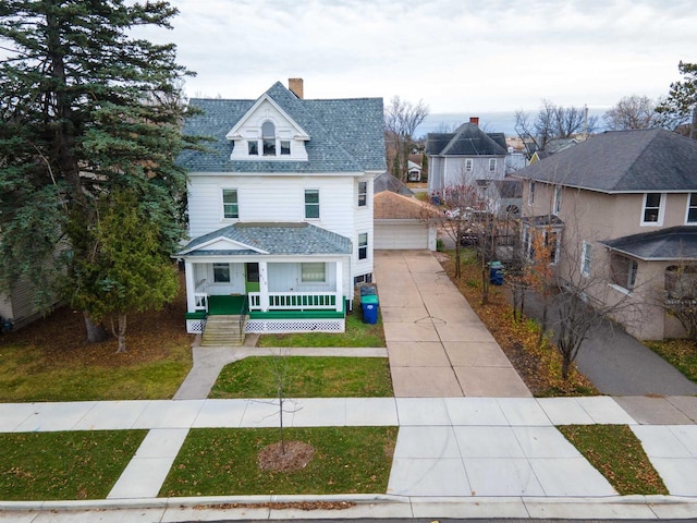 view of front facade with covered porch, a garage, a front lawn, and an outdoor structure