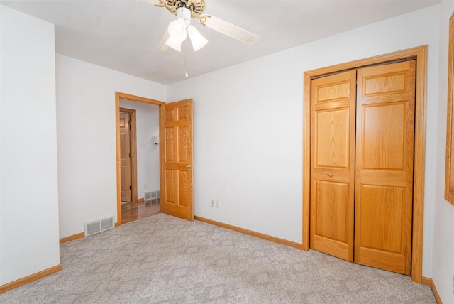 unfurnished bedroom with ceiling fan, light colored carpet, and a closet