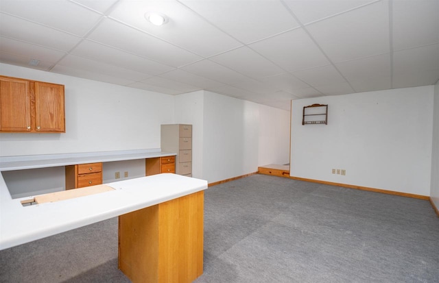 bar with a paneled ceiling, built in desk, and light carpet