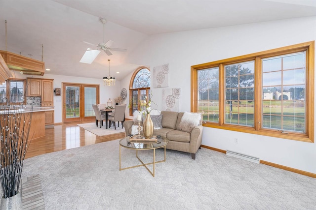 living room featuring ceiling fan with notable chandelier, a baseboard radiator, light hardwood / wood-style floors, and vaulted ceiling