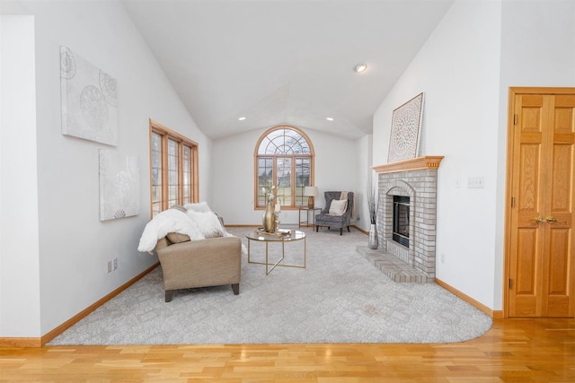 living room with a brick fireplace, hardwood / wood-style flooring, and vaulted ceiling