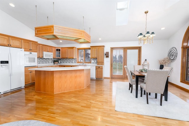 kitchen featuring tasteful backsplash, sink, white appliances, and a center island