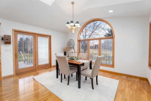 dining room with vaulted ceiling, plenty of natural light, and light hardwood / wood-style floors