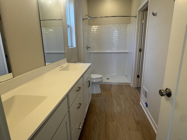 bathroom featuring tiled shower, toilet, vanity, and hardwood / wood-style flooring