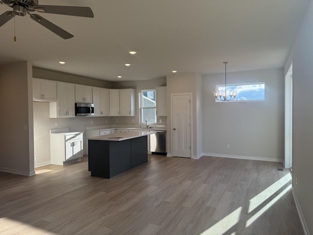 kitchen with appliances with stainless steel finishes, light hardwood / wood-style flooring, white cabinets, a center island, and hanging light fixtures