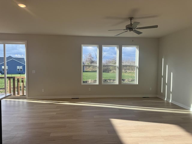 unfurnished room featuring dark hardwood / wood-style flooring, ceiling fan, and a healthy amount of sunlight