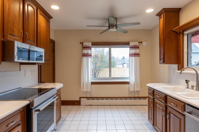 kitchen featuring stainless steel appliances, plenty of natural light, a baseboard heating unit, and sink