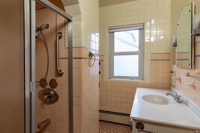 bathroom featuring vanity, a shower with shower door, tile walls, and a baseboard heating unit