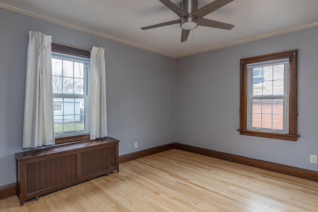 unfurnished room with radiator, a wealth of natural light, ceiling fan, and light hardwood / wood-style floors